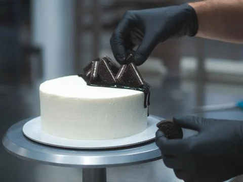 Chef decorating white icing drip cup cake with oreo cookies and dark chocolat Stock Photos