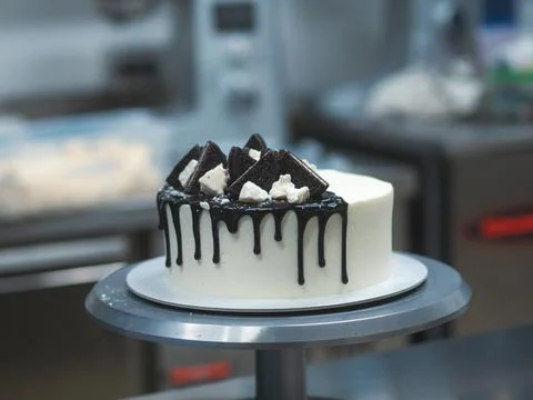 Chef decorating white icing drip cup cake with oreo cookies and dark chocolat Stock Photos