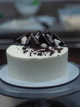 Chef decorating white icing drip cup cake with oreo cookies and dark chocolat Stock Photos