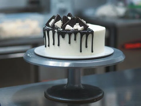 Chef decorating white icing drip cup cake with oreo cookies and dark chocolat Stock Photos