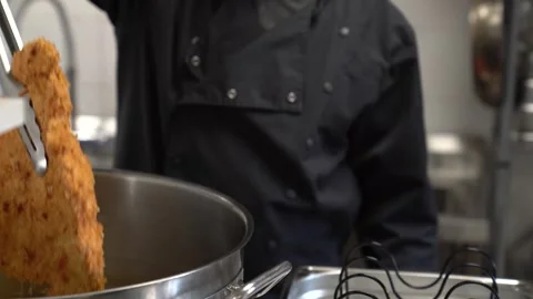 Chef deep frying breaded chicken cutlet in a professional kitchen pot Stock Footage 337899969