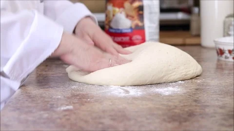 Chef deflating and kneading freshly risen bread dough into shape on a Stock Footage 121276151