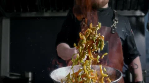 The chef deftly handles vegetables fried over an open fire in a frying pan Stock Footage 315232355