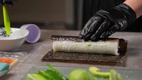 The chef deftly wraps a sushi roll in a sheet of seaweed Vidéo 289540187