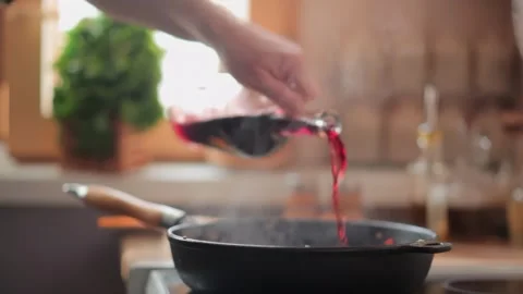Chef deglazing sauteed vegetables with red wine in a hot pan Stock Footage 314377656
