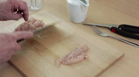 Chef dicing slices of chicken breast with a cleaver knife on a chopping board Stock-Footage 62412880