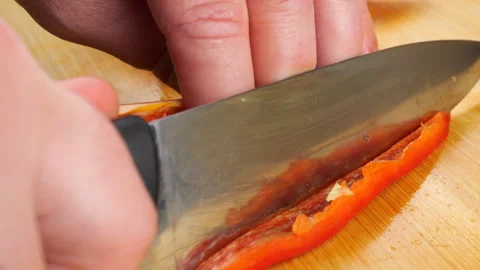 A chef dicing sweet red bell pepper on a wooden cutting board.  Video stock 341529741