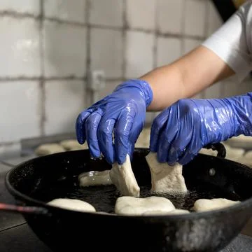 Chef dipping raw dough in boiling oil. Fresh baking, cooking process. Cook in Stock Photos