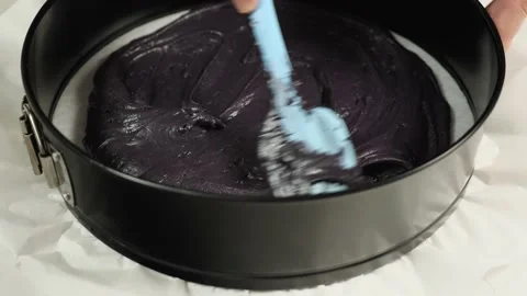 A chef distributing the black mass to make a biscuit cake in a baking mold Vídeo Stock 200809091