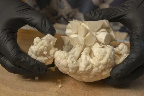 Chef divides a head of cauliflower into florets on a kitchen cutting board... Stock Photos