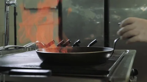 Chef doing flambe to dish in pan with large fire flame in seafood restaurant Stock Footage 81588503
