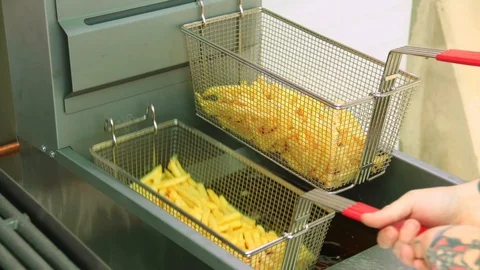 Chef draining the oil and shaking a basket full of perfectly cooked french fr Stock Footage 127715896
