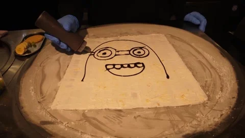 Chef Drawing Cartoon Character with Chocolate Syrup on Rolled Ice Cream Base Stock Footage 345293340