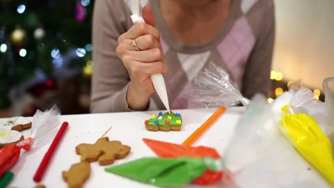 Chef draws colorful patterns on gingerbread cookies with a pastry bag with icing Stock Footage 255633365