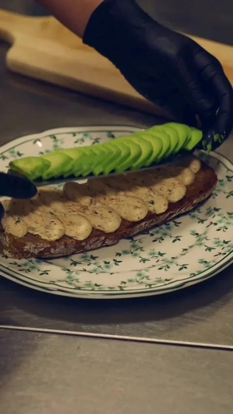 Chef drizzling balsamic glaze over gourmet avocado toast with poached egg Stock Footage 341578773