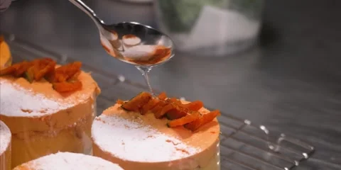 Chef Drizzling Syrup Over Mini Orange Cakes with Powdered Sugar and Candied Peel 스톡 동영상 343589051