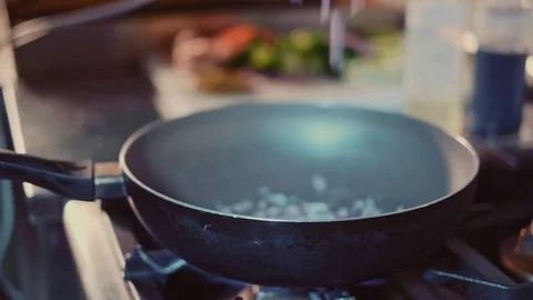 Chef dropping sliced onion in to a frying pan Stock Footage 104198219