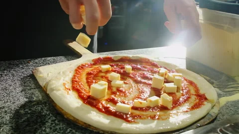Chef drops cheese cubes scattered toward rim during topping step Stock-Footage 325070703