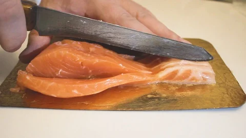 The chef effectively slices red fish into long pieces. Preparing red serve fish Video stock 126597941