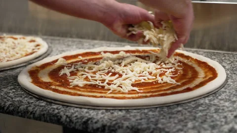 Chef evenly spreads shredded mozzarella cheese over pizza dough topped Vídeo Stock 217855623