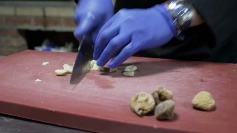 Chef at exotic restaurant preparing garlic on wood cutting board table Stock Footage 81258951