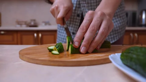 Chef expertly cuts cucumber into even circular slices on chopping board Stock Footage 329062586