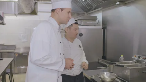 Chef explaining how to use fryer to young employee Stock Footage 125049339