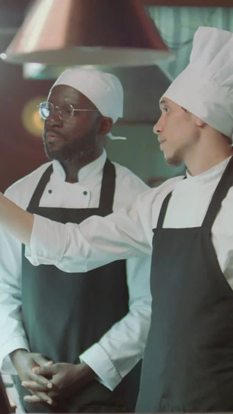 Chef Explaining Order Ticket to Apprentice in Restaurant Kitchen Stock Footage 273543574