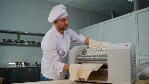 Chef Feeding Dough into Dough Rolling Machine Video stock 299655695
