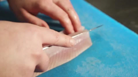Chef fillets cuts out bones of the white fish fillet on cutting board with a Stock Footage 203577894