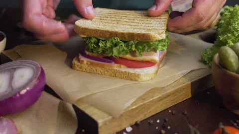 Chef finalizes the sandwich with ham and salad on the wooden board Stock Footage 143777983