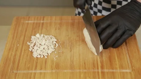 Chef finely chopping boiled chicken fillet into small cubes on a wooden cutting Stock Footage 340552481