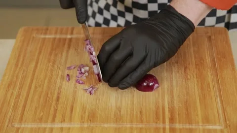 A chef finely dicing red onion into small cubes on a cutting board using a knife Stock Footage 340553832