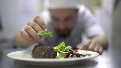 Chef is finishing meal teasty beef steak with salad for guest of restaurant Stock Footage