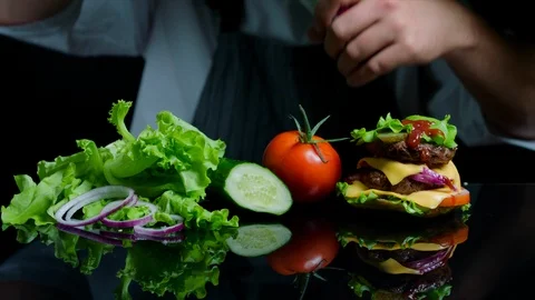 Chef finishing the savory burger with beef, cheese and vegetables. Black Stock Footage 92507541