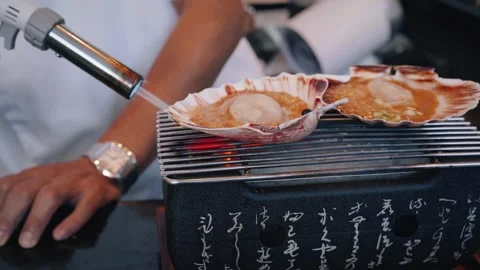 Chef flambéing scallops on BBQ shells closeup Stock Footage 317456797