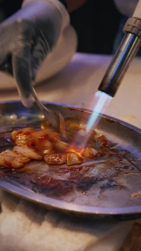 Chef flambeing soft scallops with eel sauce – 4K vertical close up night Stock Footage 315509441