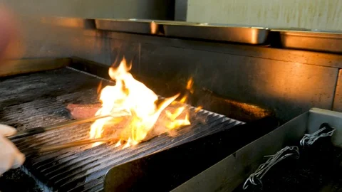 Chef flames steak on grill as camera moves Stock Footage 94262877