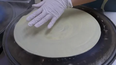 Chef Flipping a Freshly Baked Thin Crepe on a Round Hot Griddle Video stock 345651351
