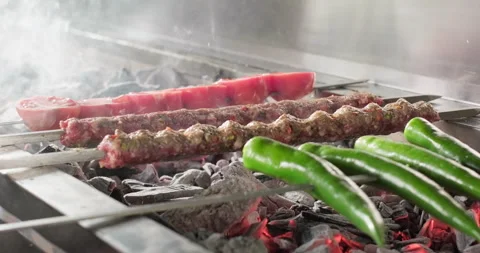 Chef flips Adana kebab grilling with vegetables on barbecue charcoal grill Stock Footage 288031540