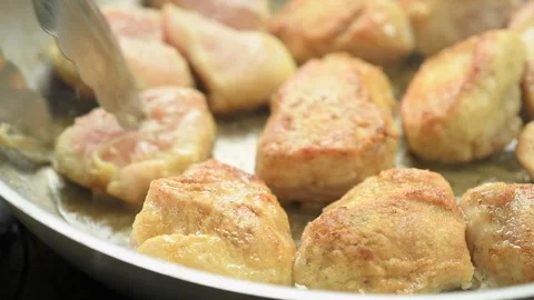 The chef flips chicken pieces to the other side in the pan with cooking tongs. Stock Footage 234892231