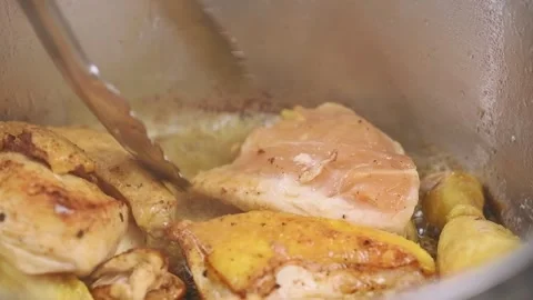 Chef flips chicken pieces in a saucepan with kitchen tongs. Stock Footage 153457985