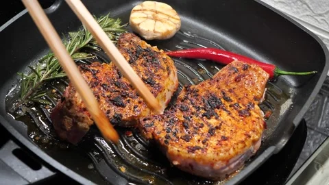 Chef flips a delicious steak with cooking tongs Stock-Footage 306862375
