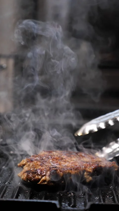 The chef flips the delicious steak with culinary tongs in a frying pan. frying Stock Footage 309197115