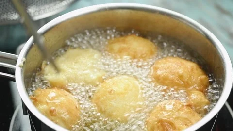 The chef flips the donuts in the pan of oil to fry them. Stock Footage 209926691