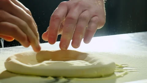 Chef flips dough forming pizza circle on floured counter Video stock 325069589