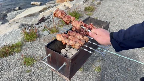 Chef flips meat over glowing charcoal. Urban street food vendor skillfully Stock Footage 327916534