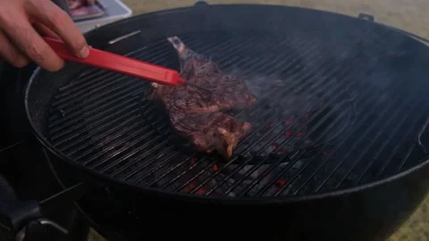 The chef flips the pieces of meat with forceps Stock Footage 148082229