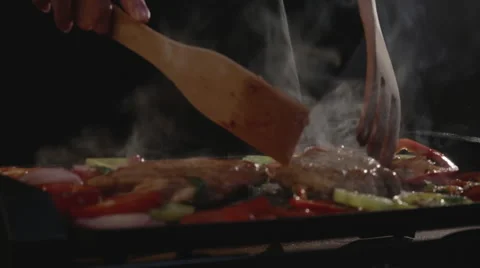 Chef flips pieces of steaming meat Stock Footage 67761723