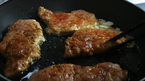Chef flips pork chops in a skillet. Close-up of pork chops are fried in a frying Stock Footage 102770076